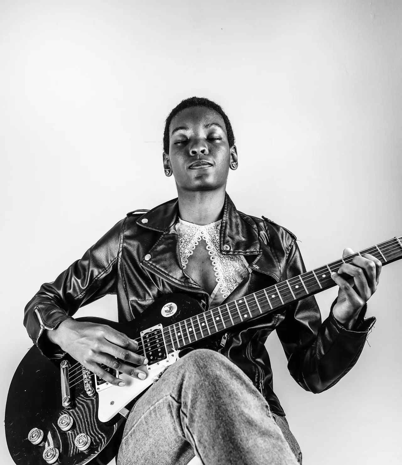 man in black leather jacket playing electric guitar